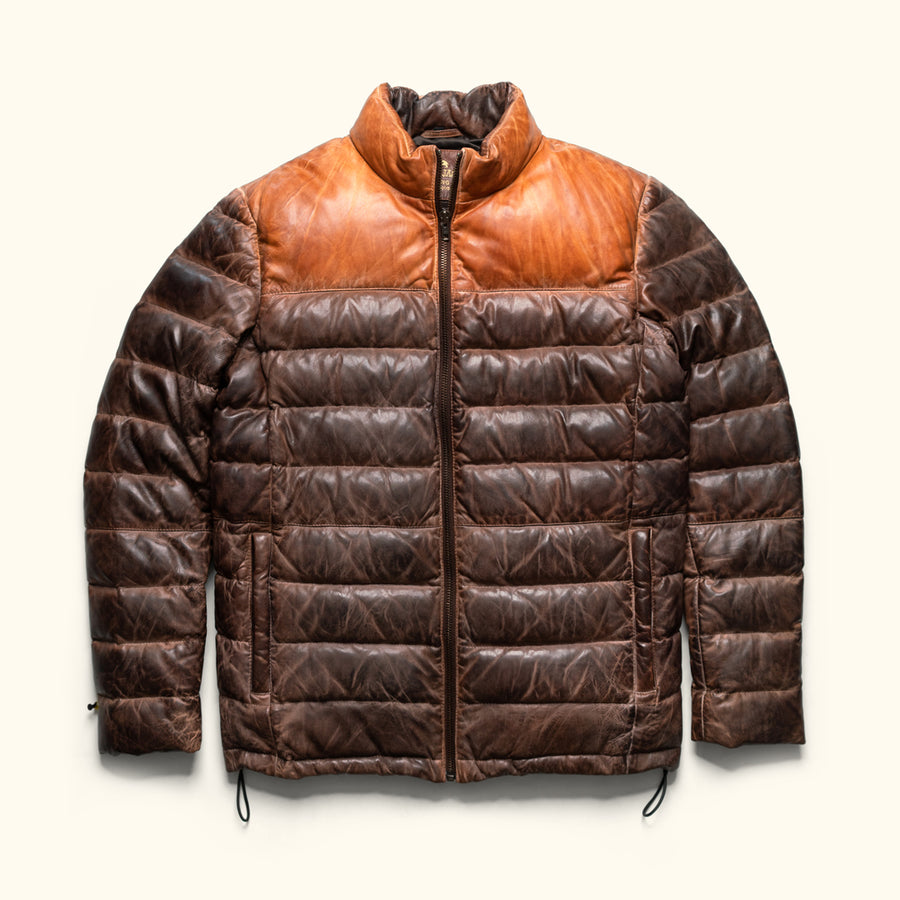 Man wearing a brown leather puffer jacket with a contrasting collar, standing outdoors with a confident expression.