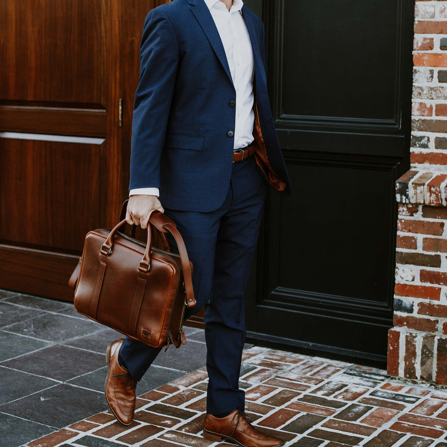 Executive-style tan leather briefcase, featuring a smooth exterior and robust carrying options.